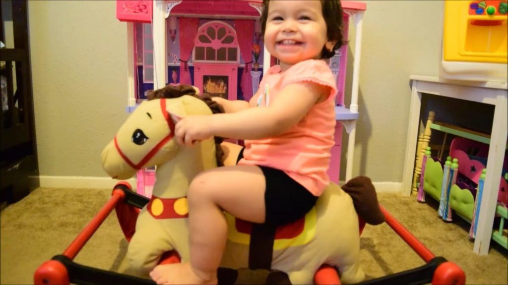 toddler girl is rocking and bouncing on radio flyer soft rock and bounce rocking pony horse