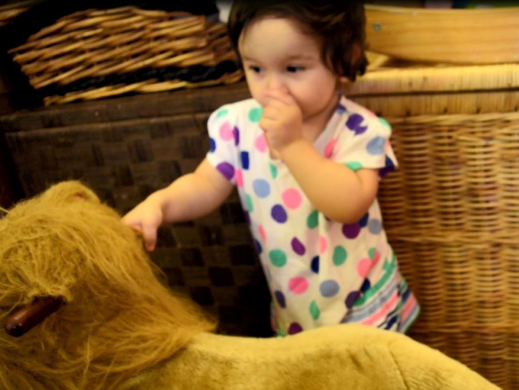 toddler standing beside the rocking animal lion rocker